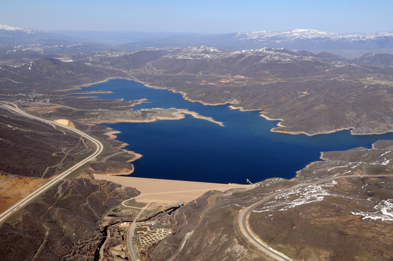 Aerial view of a mountain reservoir and its dam, roads winding along the shoreline